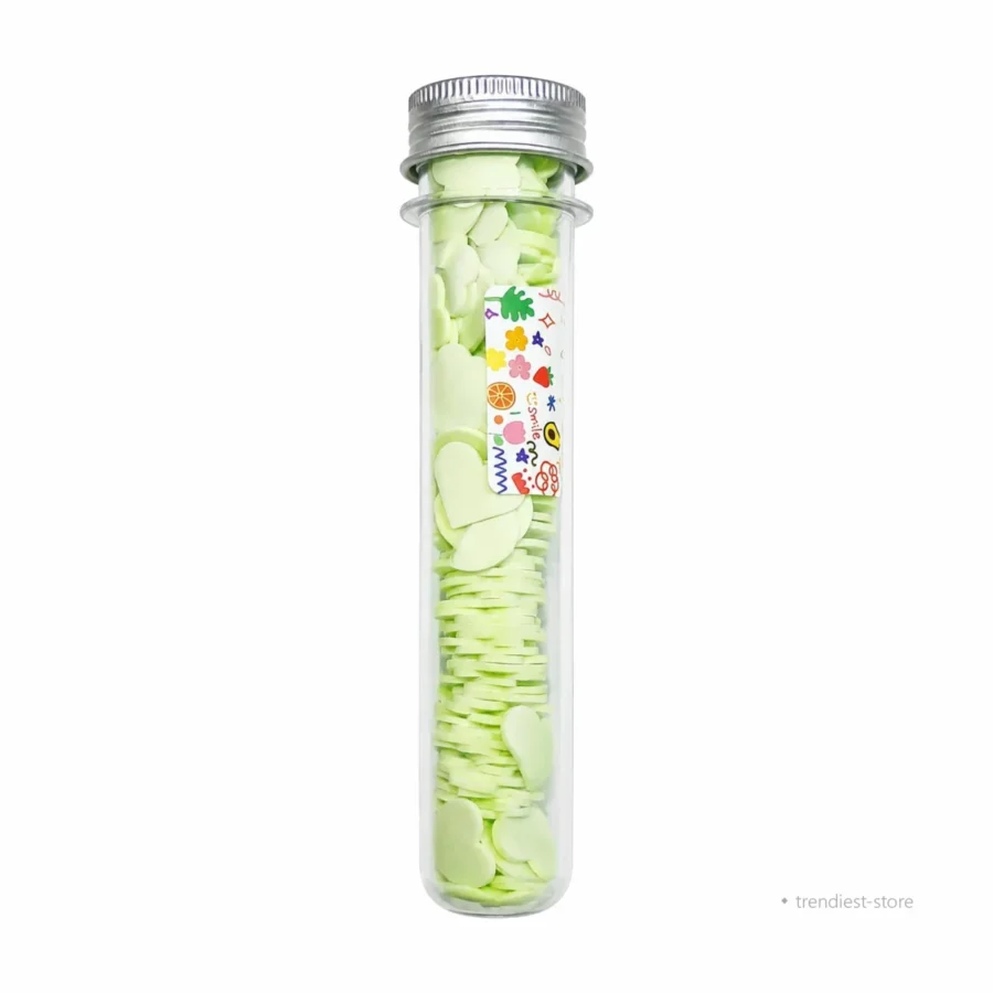 A clear glass tube with a silver metal screw cap, filled with pale green wax melts. A small decorative label with colorful flowers and Japanese text is attached to the tube.