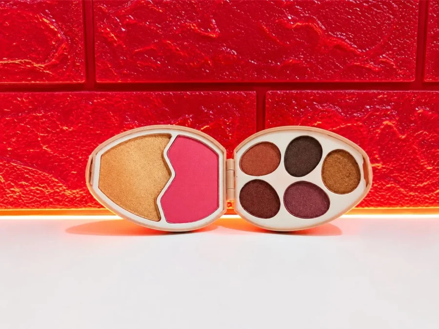 Open egg makeup palette showing five eyeshadows with blush and highlighter