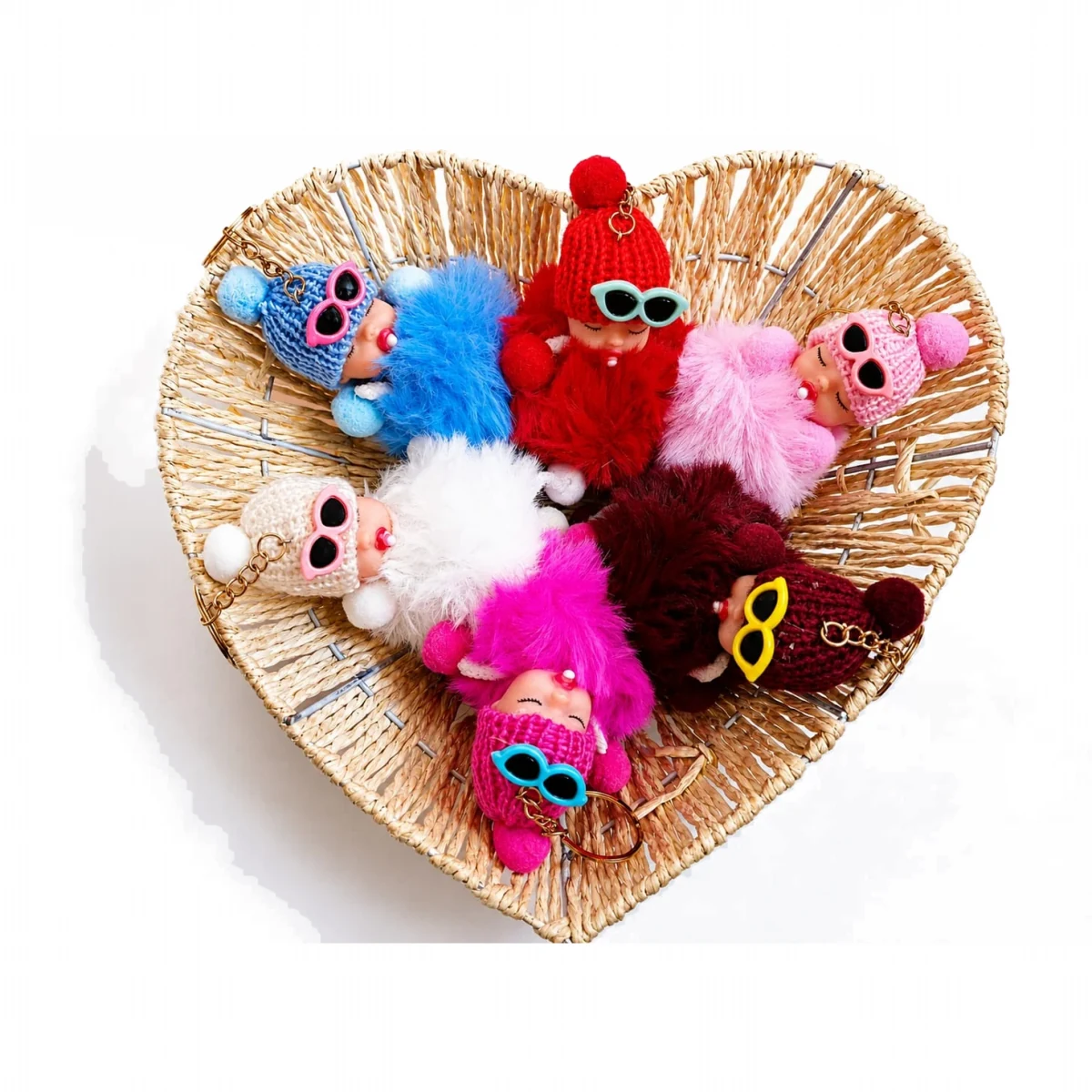 Sleeping baby doll pom pom keychains arranged in a heart shaped basket
