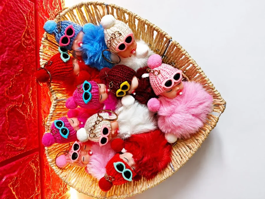Collection of fluffy sleeping baby doll keychains in a woven basket